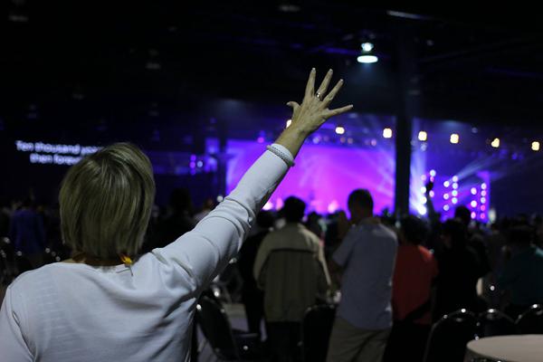 A woman prays in a large Christian conference. 