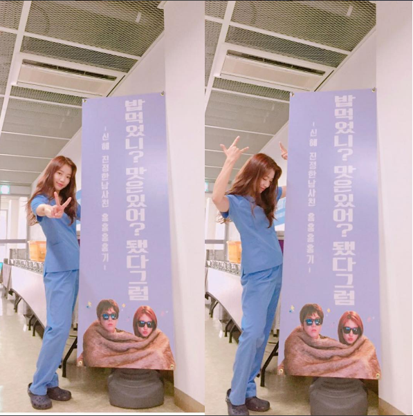 The picture is of Park Shin-hye standing in front of a food truck that Lee Hong-Ki sent. She's posing with a V and her hands up above her head.
