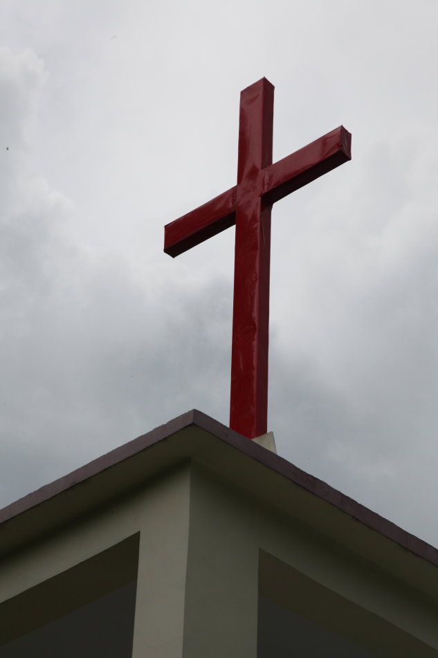 A cross stands on the top of a church in Hainan