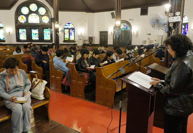 A sister leads the congregation to read the Bible in Chongwenmen Church 