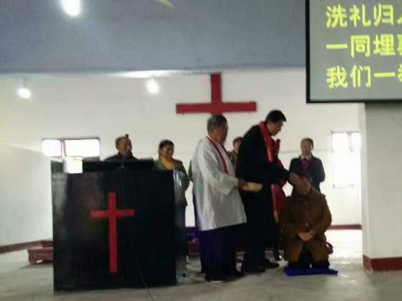 A pastor baptizes a man in Shen'en Church 