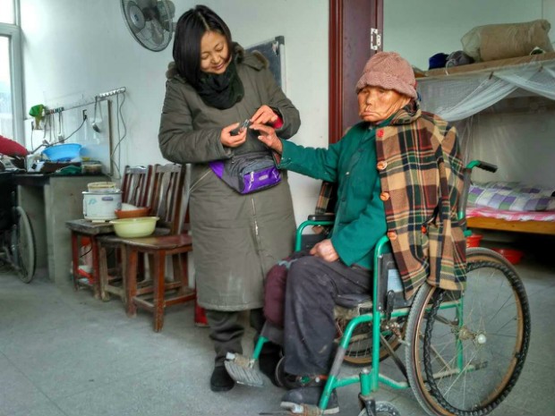 Sister Qiao trims the nails of an elderly leprosy survivor 