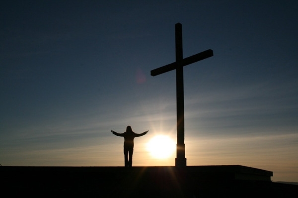 A women stands beside a cross
