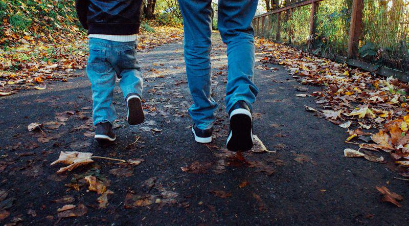 A father and a son walk on the road