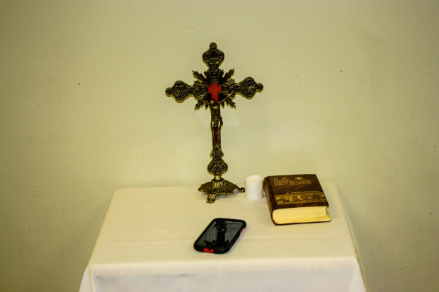 The Bible and a cellphone are placed on a desk. 