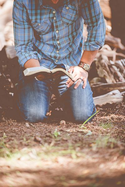 A man reads the Bible on his knees. 
