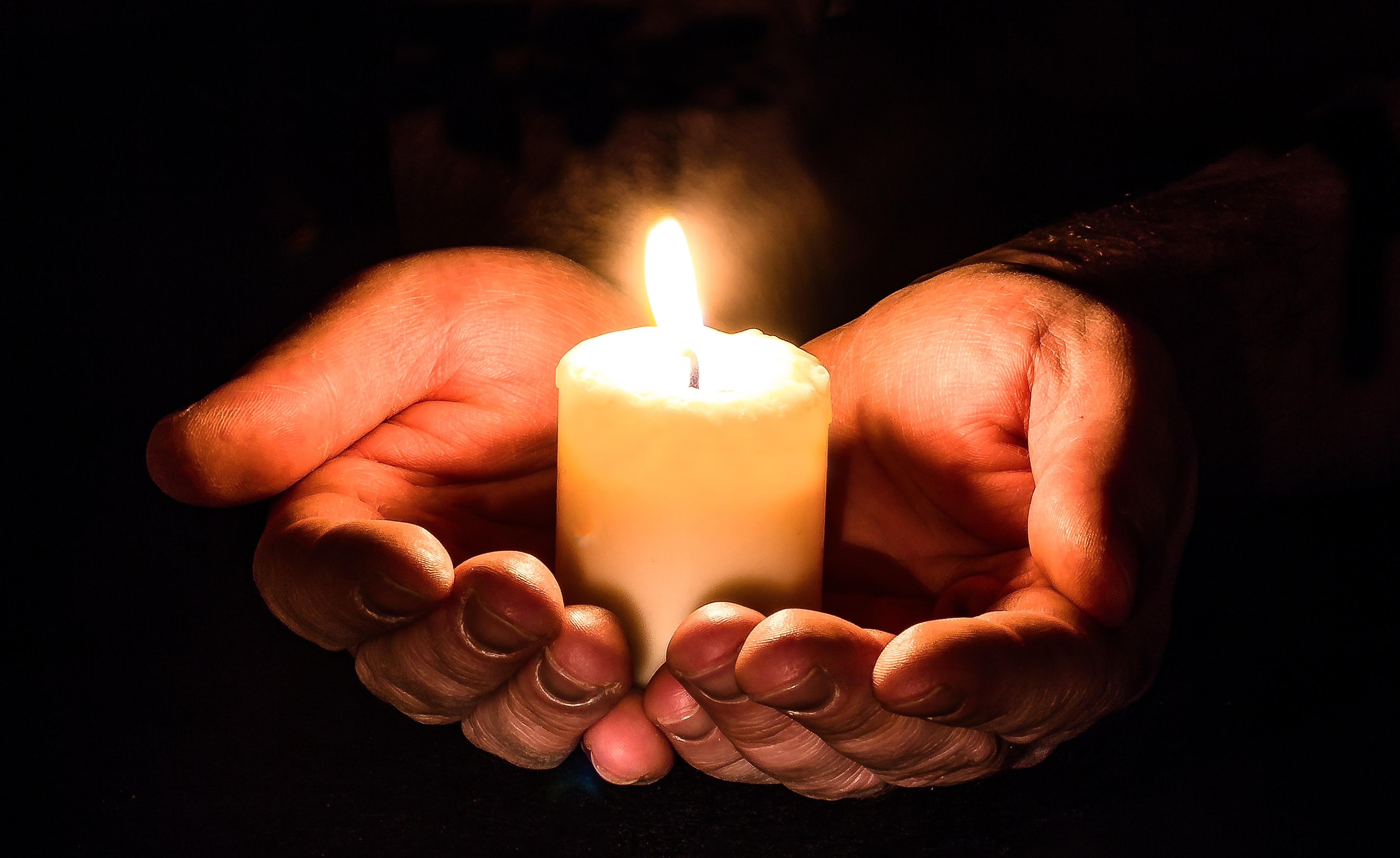 A man holds a candle in his hands. 