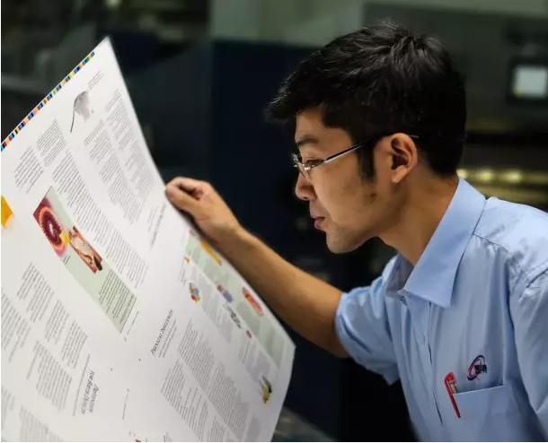 A worker of Amity Printing Company looked at a printed paper. 