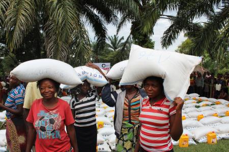(Left to right) Terese Bitota, Julie Mujinga, Elise Mbonda and Renadette Kapinga carry sacks of corn flour they received from CEM. 