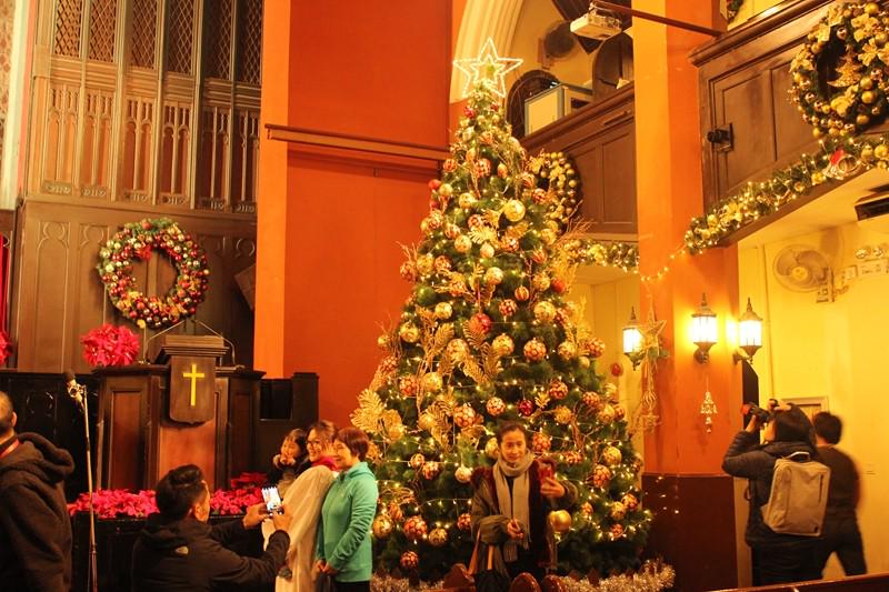 Some believers took photos in front of the Christmas tree placed in Shanghai Community Church on Dec. 24, 2019. 