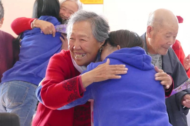 Elderly people hug each other. 