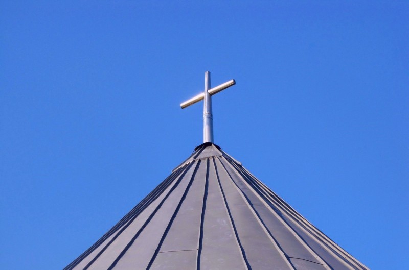 A cross stands on the top of a church. 