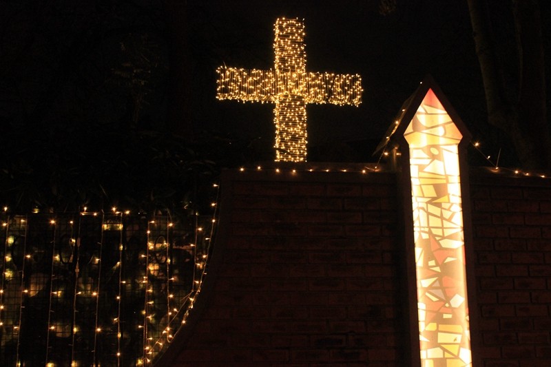 A cross stands outside of a church fence.