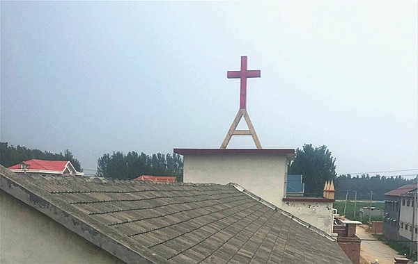 A cross stand atop a rural church. 