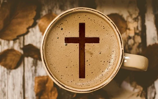 An imgae of a cross is on coffee. 