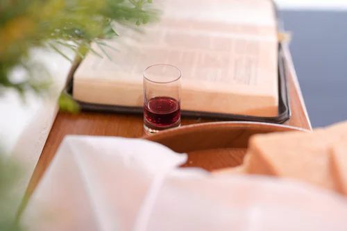 A cup of wine and bread are placed beside the Holy Bible. 
