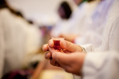 A person holds a cup of grape juice to receive Jesus' blood at the Communion service. 