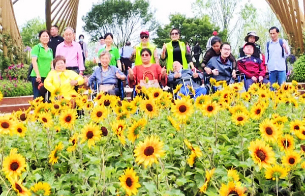 People with disabilities on wheelchairs took a picture before sunflowers with their family members and the volunteers of Reed's Family in Yizheng Expo Park in Yangzhou, Jiangsu on May 13, 2021.