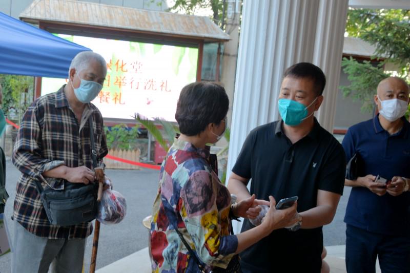 A church staff teaches an elderly believer how to show her health code to enter the sanctuary.