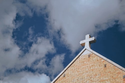 A church cross under the blue sky.