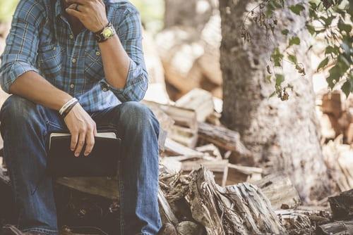 A man sits near a tree.