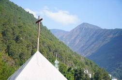 A cross on a church among mountains.