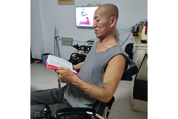 Wang Zhangwei read the Bible in a wheelchair in Linfen, Shanxi Province, on August 10, 2021. 