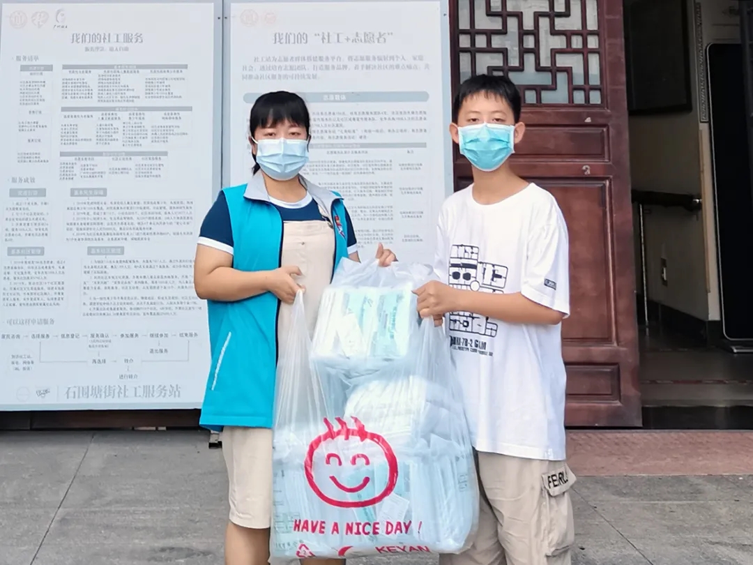 A student with the surname of Zhou, who donated 1000 masks, stood with a staff worker of Shiweitang Street Social Work Service Station operated by Guangzhou YMCA on August 28, 2021.