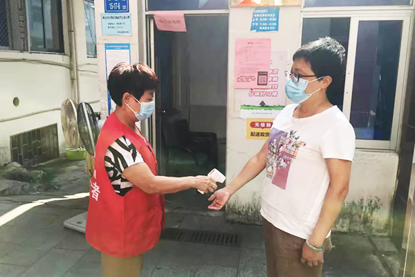 A volunteer of Xiamen Ren’ai Love Service Center in Fujian checked the temperature of a woman in September 2021.