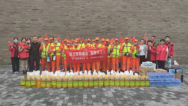 Volunteers of Xi'an YMCA in Shaanxi and sanitation workers took a group picture with pandemic prevention gift packages in front of them on September 30, 2021.