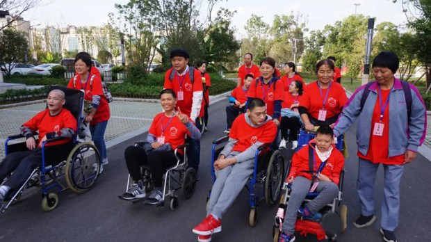 Volunteers from Reed's Home pushed the chair of children with cerebral palsy in a walk during a family camp held in Yangzhou, Jiangsu, on October 18-20, 2021.
