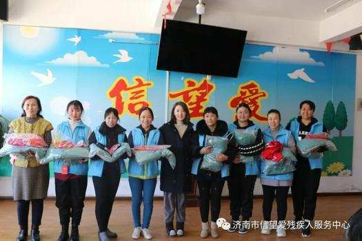Mrs. Fang Xintian gave donations to the teachers holding new school uniforms of the Faith & Hope & Love Center Disability Service Center in Jinan, Shandong Province, in November 2021.