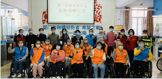 People with spinal cord injuries and volunteers took a group picture during a donation ceremony by Xiamen YMCA in Xiamen Halfway House in Xiamen, Fujian for disabled persons on Decemver 8, 2021.