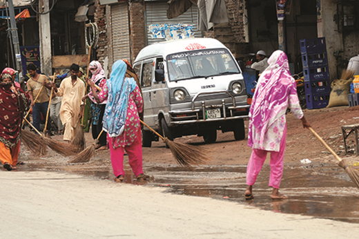 Women and men are engaged in janitorial work on the street.