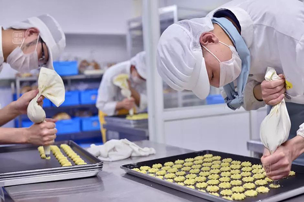 Mentally handicapped employees at the Amity Bakery in Nanjing, Jiangsu, squeezed dough to make cookies at an unknown day.