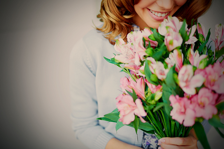 A picture show a woman holding a bouqued of pink flowers.