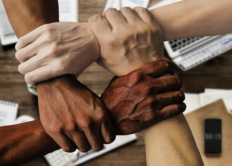 A picture shows four hands of different colors are joining together.