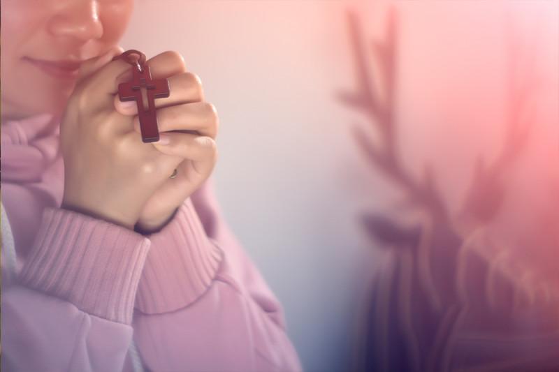 A girl holds a cross to pray.