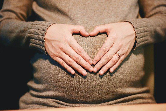 A picture shows apregnant mother is making a heart gesture over her belly.
