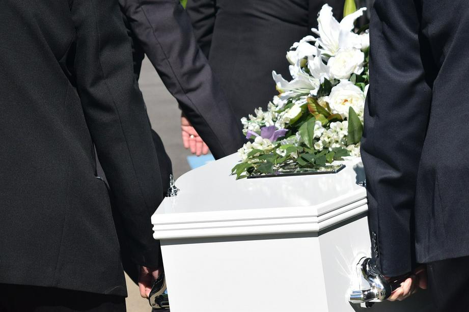 A picture shows several people carryinng a white coffin with flowers on it.