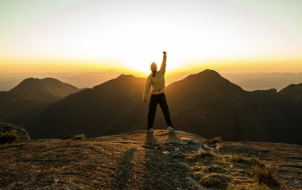 A picture shows a young mann toward the sun raising his fist.