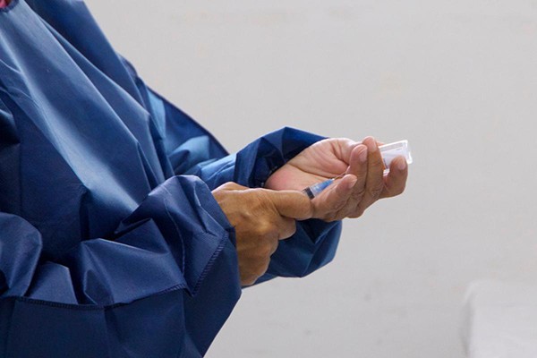 A picture shows a medical worker preparing a dose for vaccination.