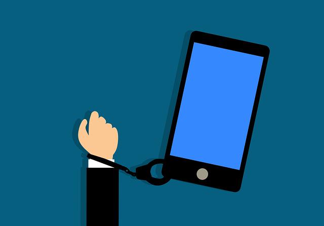 A picture shows a hand handcuffed to a smart phone.