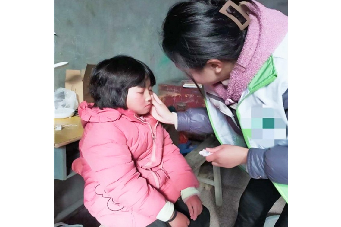A picture shows a volunteer putting creams on a child at an unknown date.