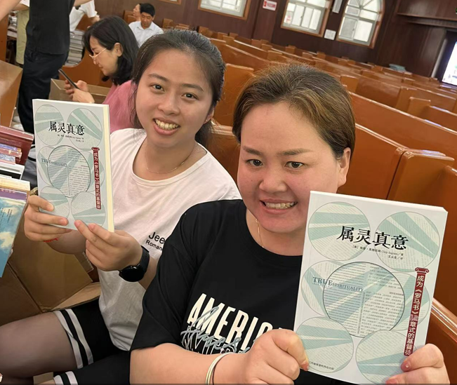 Two graduates happily held the book True Spirituality given by Jiangsu Theological Seminary on June 17, 2022.