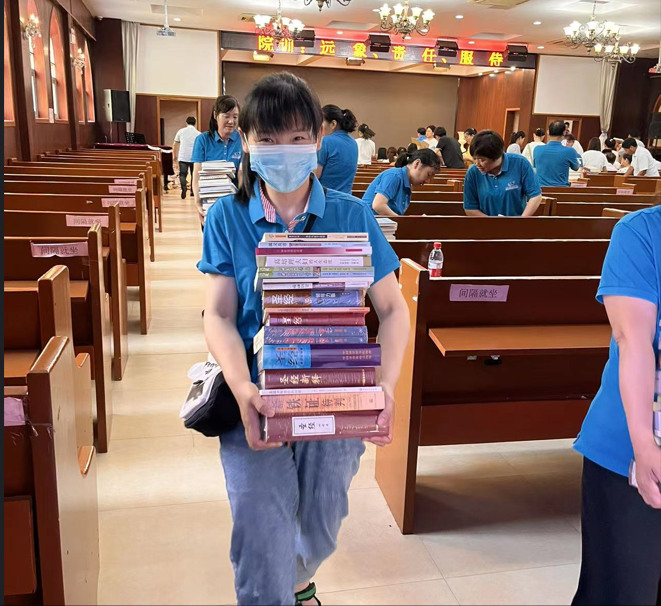 A junior college graduate in the pastoral class of Jiangsu Theological Seminary held a stack of spiritual books given to each as gifts during the commencement ceremony on June 17, 2022.