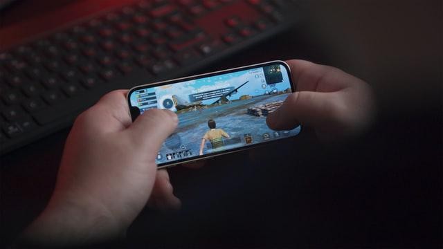 A picture shows a person holding a mobile phone to play a game.