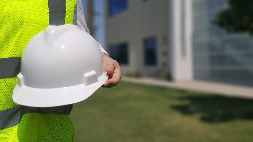 A pictures shows a worker holding a hard hat.