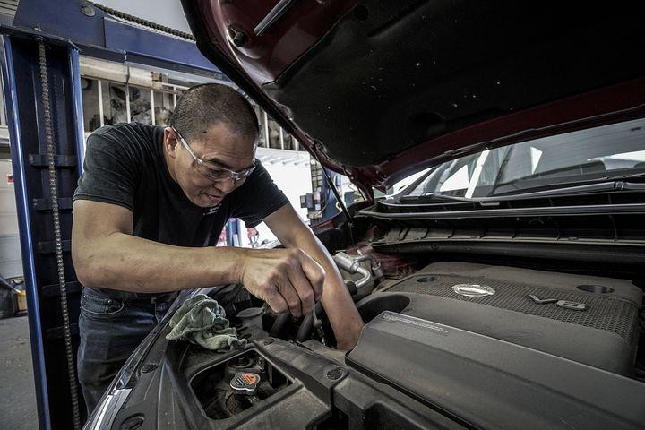 A picture shows a man repairing a car.