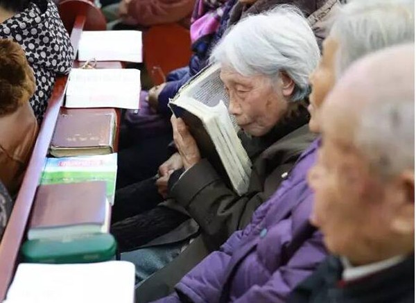 A picture shows a senior believer reading the Bible.
